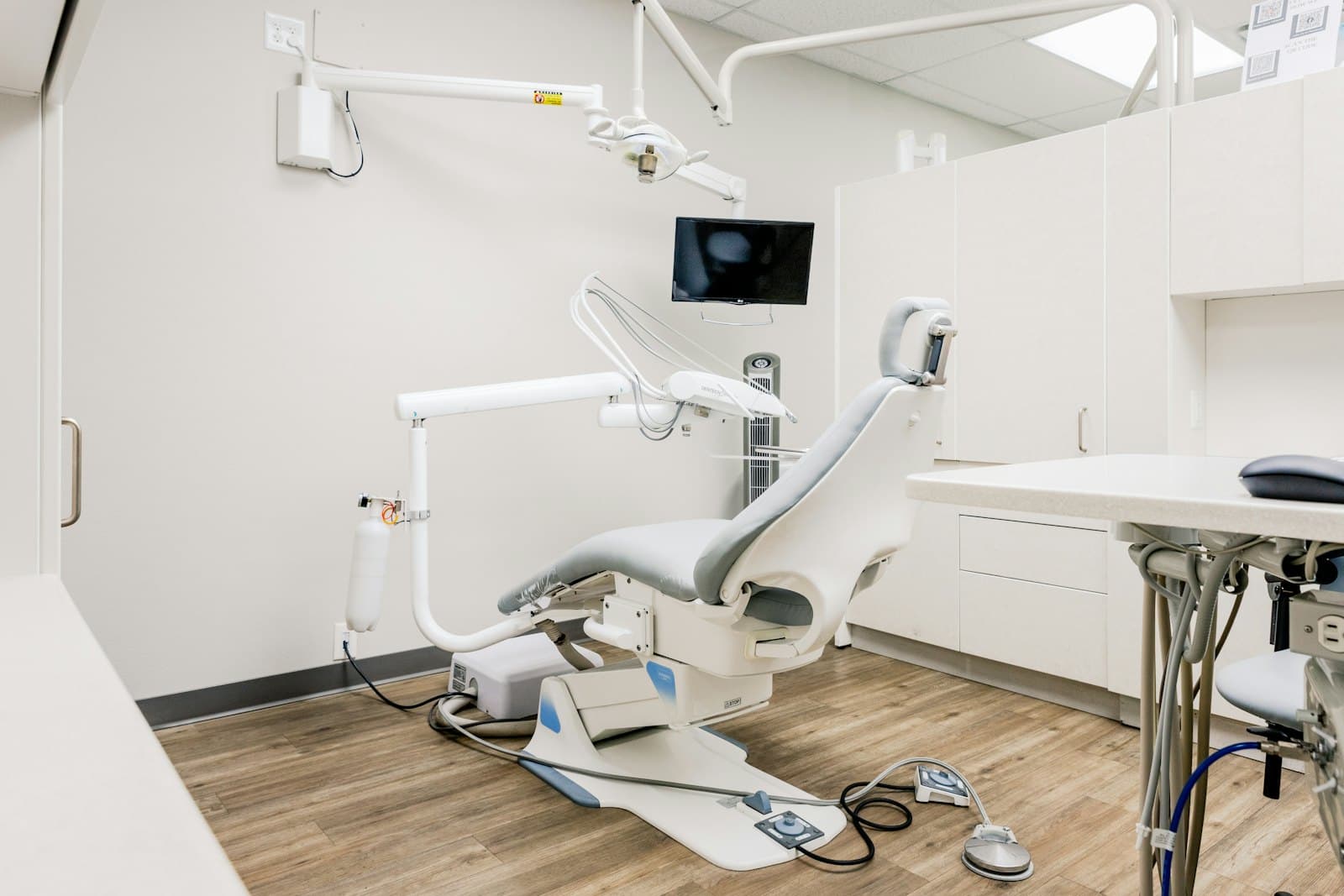Modern dental clinic operatory with chair, overhead light and equipment in a calm neutral palette